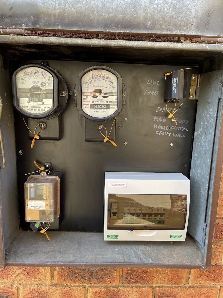 Twin meters set into a brick wall recess above a new breaker enclosure